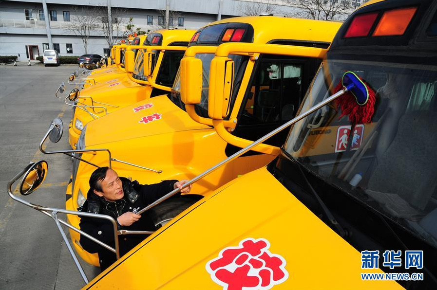 2月18日，江苏省太仓市校车驾驶员在擦拭校车前挡风玻璃。新学期开学在即，江苏省太仓市对校车展开全面安全检查，确保新学期学生乘车安全。